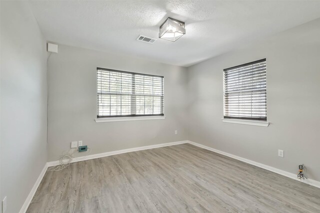 spare room featuring a textured ceiling and light hardwood / wood-style flooring