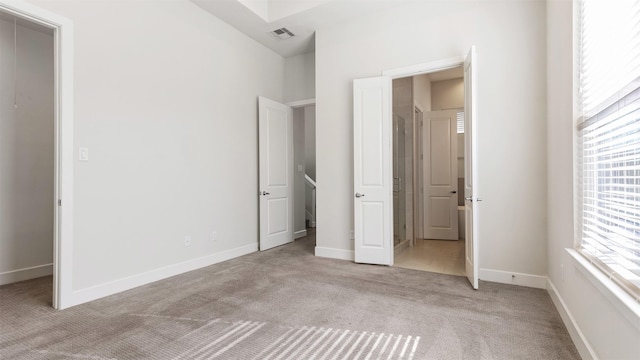 unfurnished bedroom featuring light colored carpet and a walk in closet