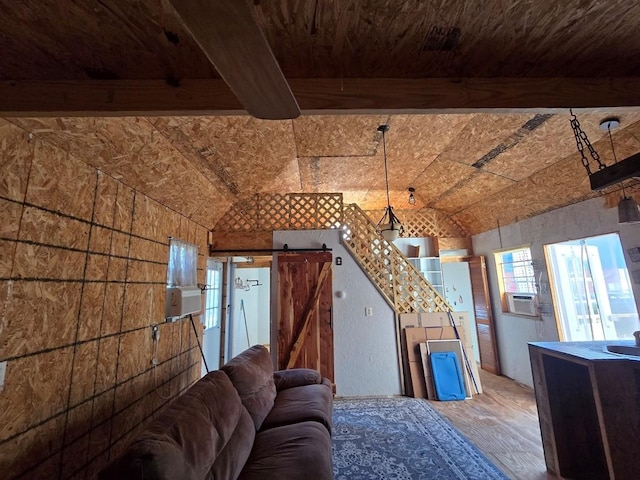 living room with brick ceiling, a barn door, beamed ceiling, and hardwood / wood-style flooring