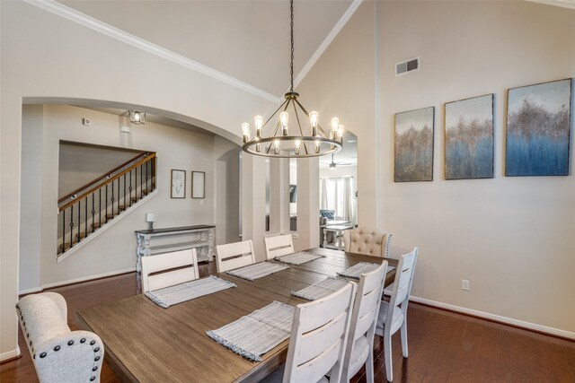 dining area featuring dark wood-type flooring, high vaulted ceiling, crown molding, and a notable chandelier