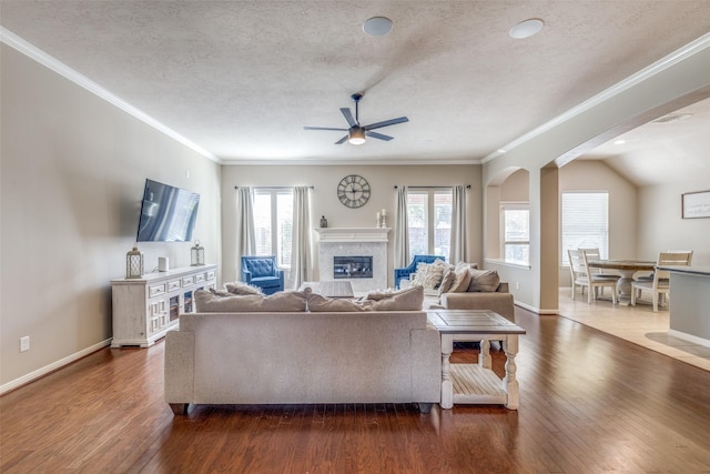 living room with ceiling fan, dark hardwood / wood-style flooring, a textured ceiling, and ornamental molding