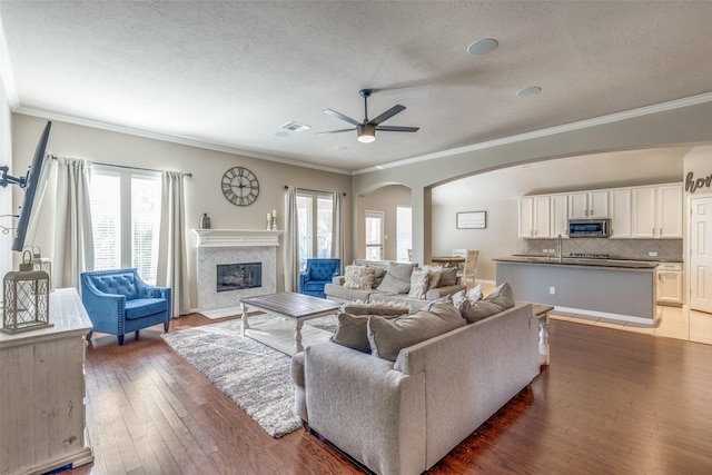 living room featuring dark hardwood / wood-style flooring, crown molding, a fireplace, and ceiling fan