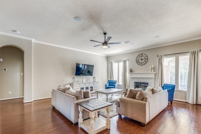 living room with a textured ceiling, crown molding, dark wood-type flooring, and a premium fireplace