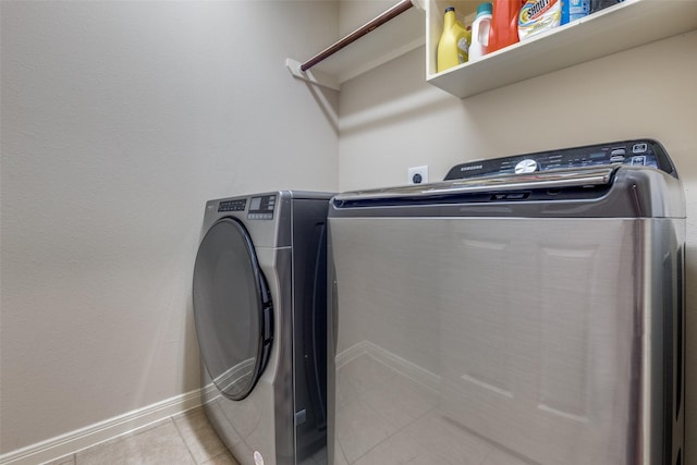 laundry area with washer and clothes dryer and light tile patterned floors