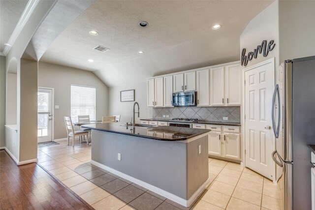 kitchen with white cabinets, stainless steel appliances, a kitchen island with sink, and sink