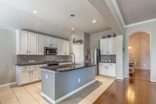 kitchen with stainless steel appliances, white cabinetry, a kitchen island with sink, and light tile patterned flooring