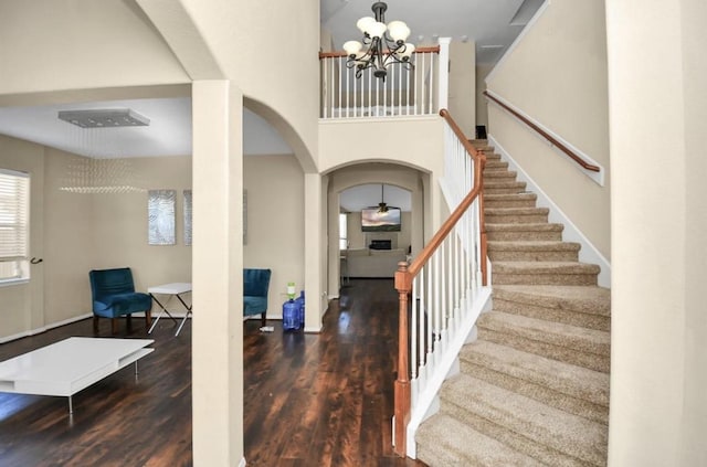 entrance foyer featuring a towering ceiling, dark hardwood / wood-style floors, and a notable chandelier