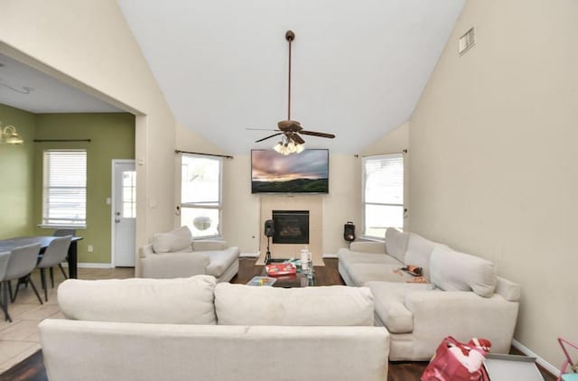 living room with tile patterned flooring, ceiling fan, a tile fireplace, and vaulted ceiling