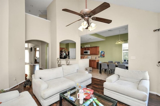 living room with a towering ceiling and ceiling fan with notable chandelier