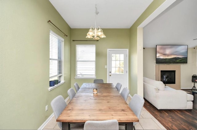 tiled dining area featuring a fireplace and an inviting chandelier