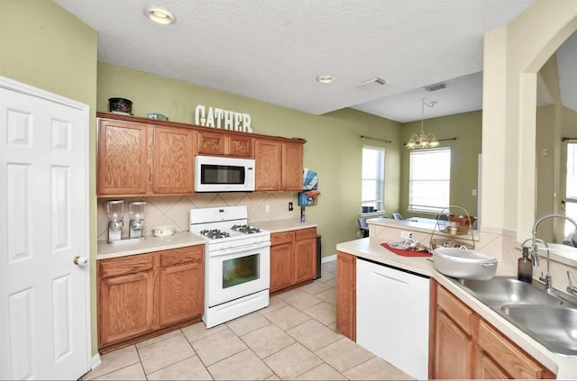 kitchen with backsplash, white appliances, pendant lighting, light tile patterned floors, and a notable chandelier