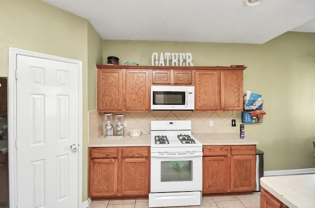 kitchen with white appliances, tasteful backsplash, and light tile patterned flooring