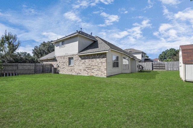 rear view of house with a yard, cooling unit, and a storage unit