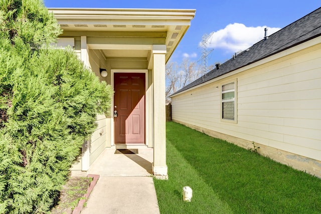 view of exterior entry with a yard