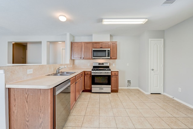 kitchen featuring sink, backsplash, kitchen peninsula, light tile patterned floors, and appliances with stainless steel finishes