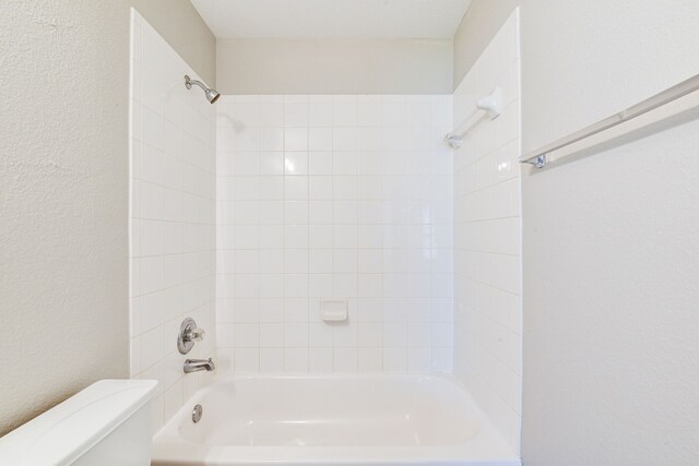 bathroom featuring toilet and tiled shower / bath