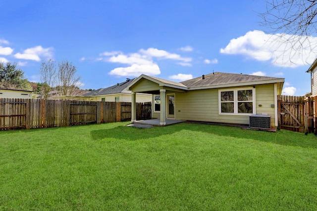 rear view of property featuring a lawn, central AC unit, and a patio area