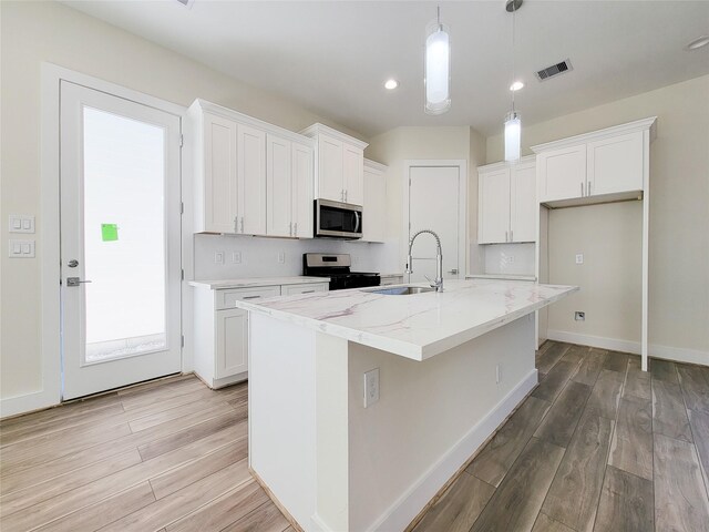 kitchen with an island with sink, sink, white cabinets, and stainless steel appliances