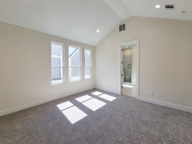 carpeted empty room with vaulted ceiling