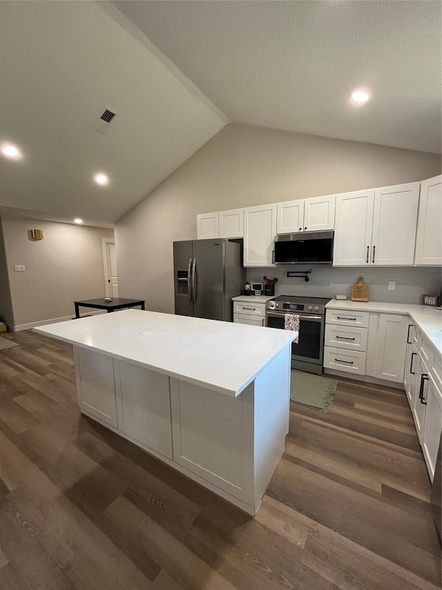 kitchen featuring white cabinetry, vaulted ceiling, appliances with stainless steel finishes, dark hardwood / wood-style flooring, and a kitchen island