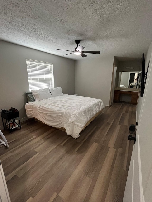 bedroom featuring dark wood-type flooring, a textured ceiling, and ceiling fan