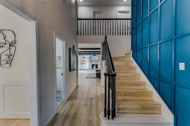 stairway with a fireplace, hardwood / wood-style floors, and a towering ceiling