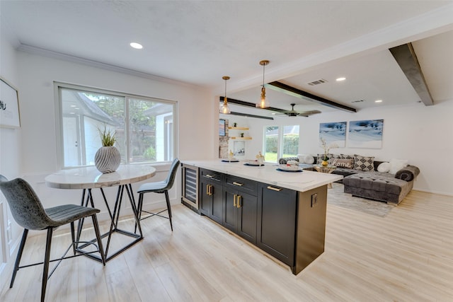 kitchen with light wood-type flooring, light stone counters, ceiling fan, decorative light fixtures, and beamed ceiling