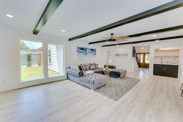 living room featuring ceiling fan, beamed ceiling, and light hardwood / wood-style floors