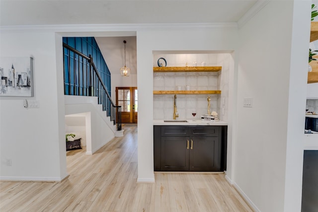 bar with backsplash, hanging light fixtures, light hardwood / wood-style floors, and ornamental molding