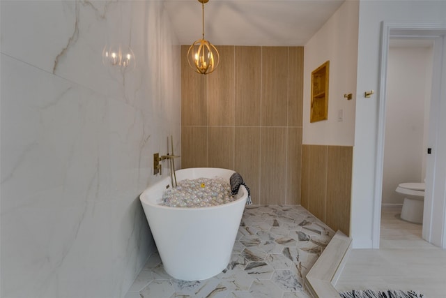 bathroom with toilet, a bathtub, and a notable chandelier