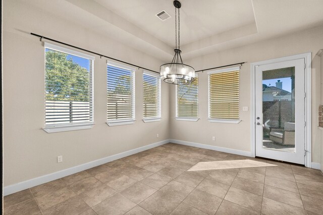 unfurnished dining area with a chandelier, light tile patterned floors, and a tray ceiling