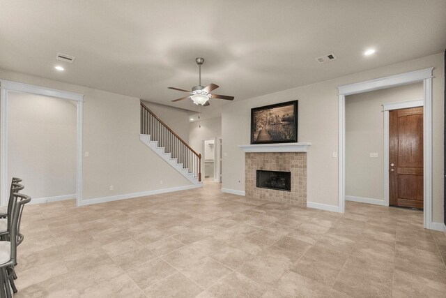 unfurnished living room featuring ceiling fan and a fireplace