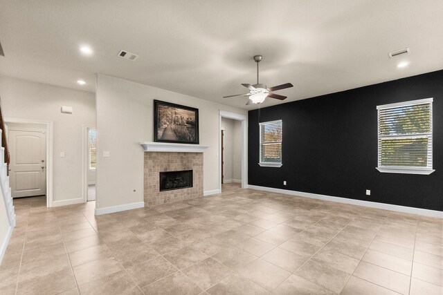 unfurnished living room featuring a tiled fireplace, ceiling fan, and light tile patterned floors