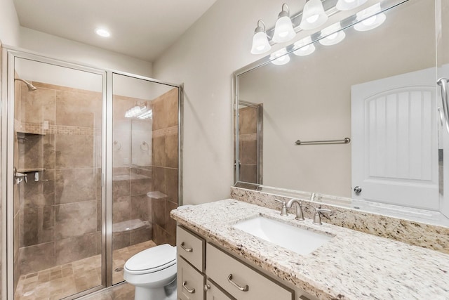 bathroom featuring vanity, a shower with shower door, and toilet