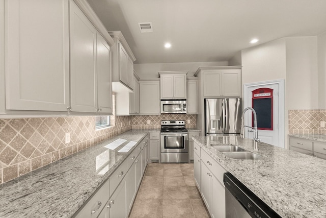 kitchen with white cabinets, light stone countertops, sink, and appliances with stainless steel finishes