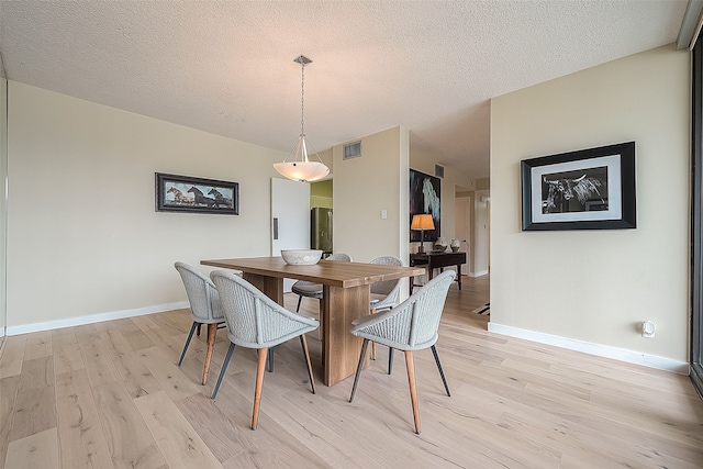 dining room with light hardwood / wood-style flooring and a textured ceiling