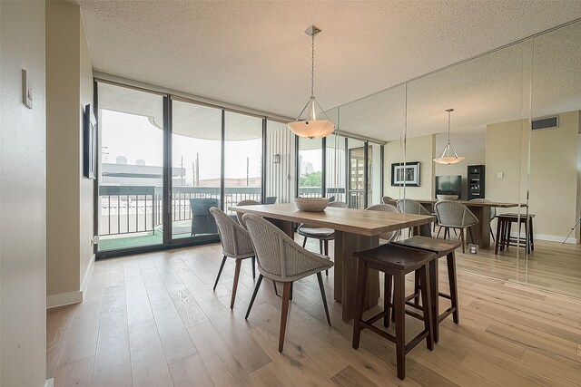 dining area featuring plenty of natural light, a textured ceiling, and a wall of windows