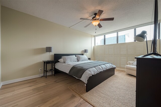 bedroom with wood-type flooring, a textured ceiling, and ceiling fan