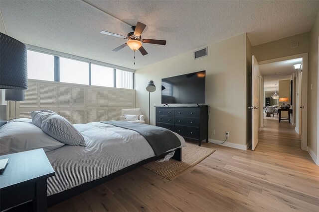 bedroom with ceiling fan, light wood-type flooring, a textured ceiling, and a closet