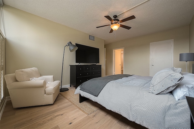 bedroom featuring ceiling fan, light hardwood / wood-style flooring, and a textured ceiling