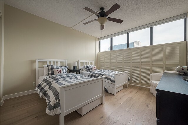 bedroom with ceiling fan, a textured ceiling, and light wood-type flooring