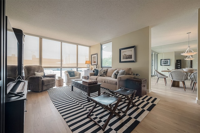 living room featuring a textured ceiling, light hardwood / wood-style floors, and floor to ceiling windows