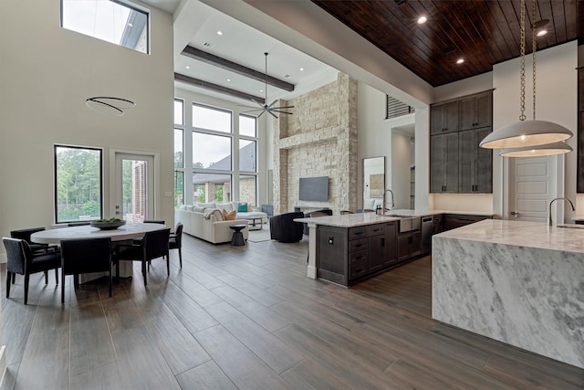 kitchen featuring dark brown cabinetry, sink, a high ceiling, kitchen peninsula, and a fireplace