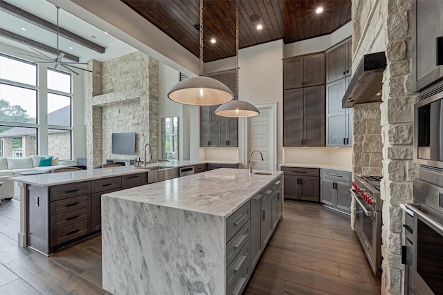 kitchen featuring appliances with stainless steel finishes, light stone counters, sink, pendant lighting, and a large island