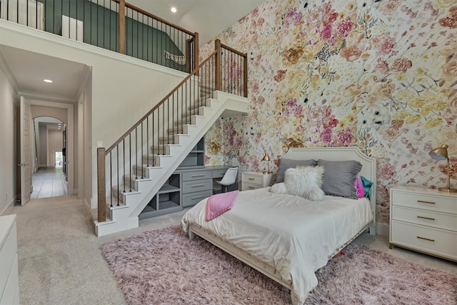 carpeted bedroom featuring ornamental molding and a towering ceiling