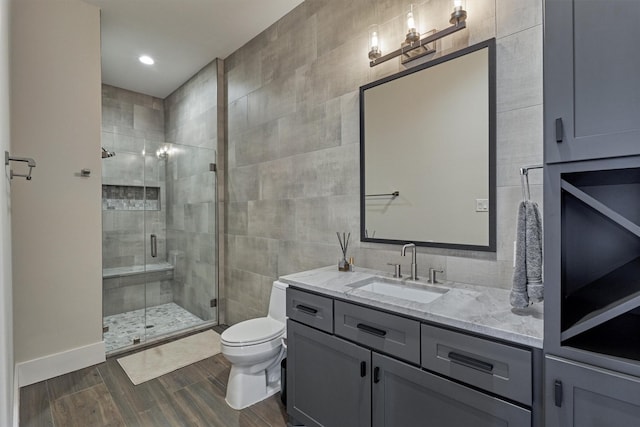 bathroom with vanity, toilet, an enclosed shower, and tile walls