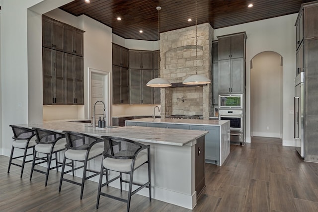 kitchen with kitchen peninsula, stainless steel appliances, a breakfast bar area, and an island with sink