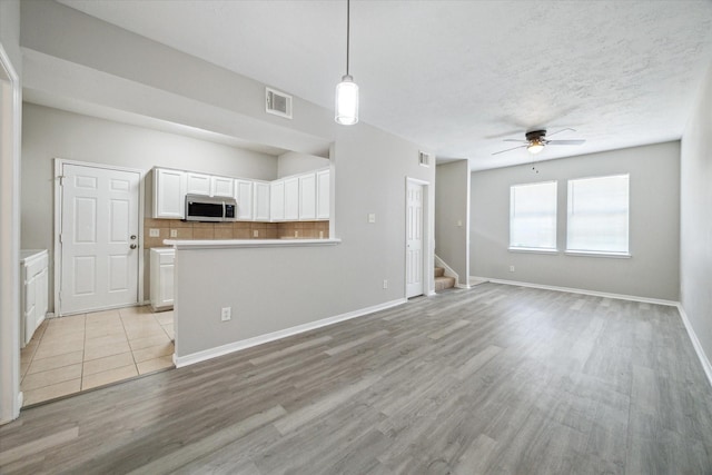 unfurnished living room with ceiling fan and light wood-type flooring