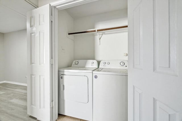 clothes washing area with washer and dryer and light hardwood / wood-style flooring