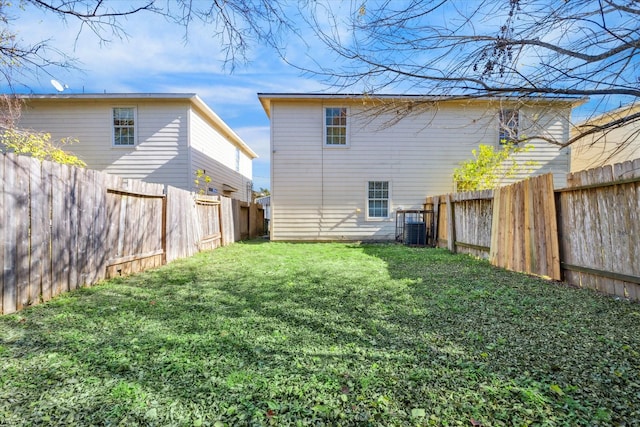 rear view of property featuring a lawn and central air condition unit